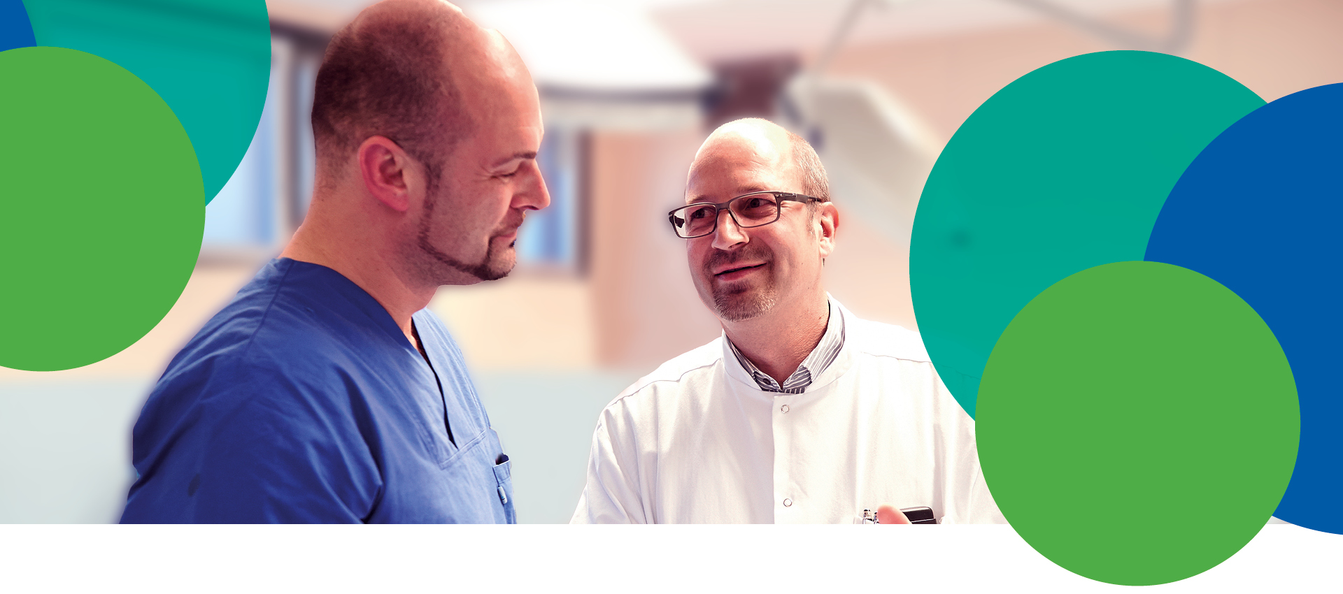Zwei männliche Mediziner, einer im blauen Kittel und einer im weißen Kittel, unterhalten sich. Der Hintergrund ist unscharf, und mehrere große grüne und blaue Kreise überlagern das Bild.