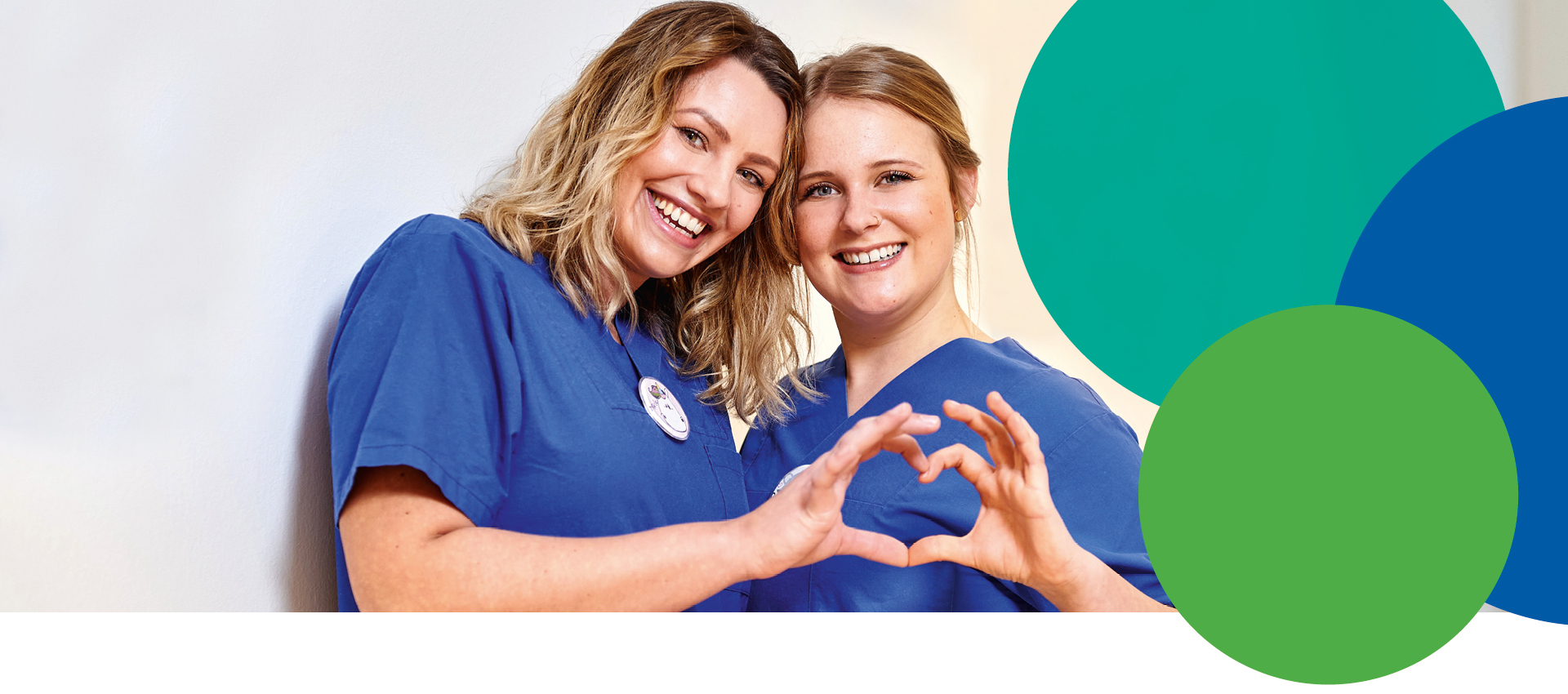 Zwei lächelnde Frauen in blauen Uniformen stehen dicht beieinander und bilden mit ihren Händen eine Herzform. Der Hintergrund besteht aus sich überlappenden blauen und grünen Kreisen auf der rechten Seite.